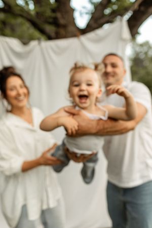 Candid outdoor family photo with white backdrop showing playful moment and laughter.