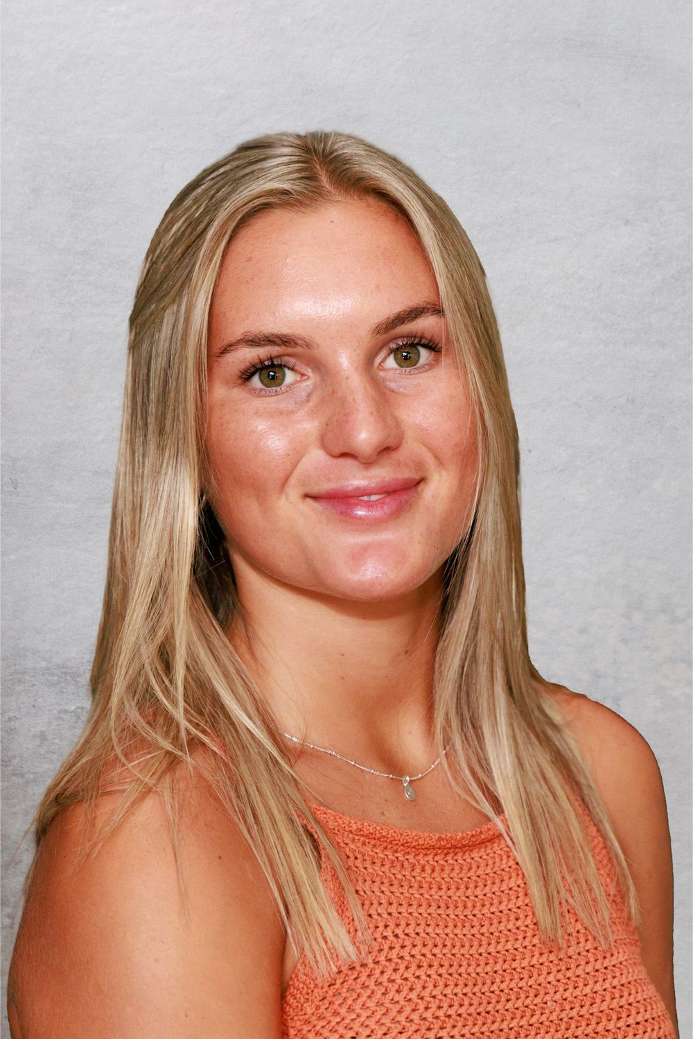 Portrait of a smiling young woman with long straight blonde hair wearing an orange knit top and delicate necklace.