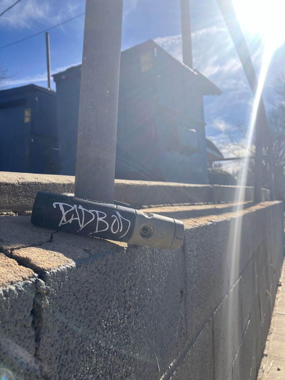 Graffiti tag written on a concrete barrier wall photographed from multiple angles in bright sunlight.