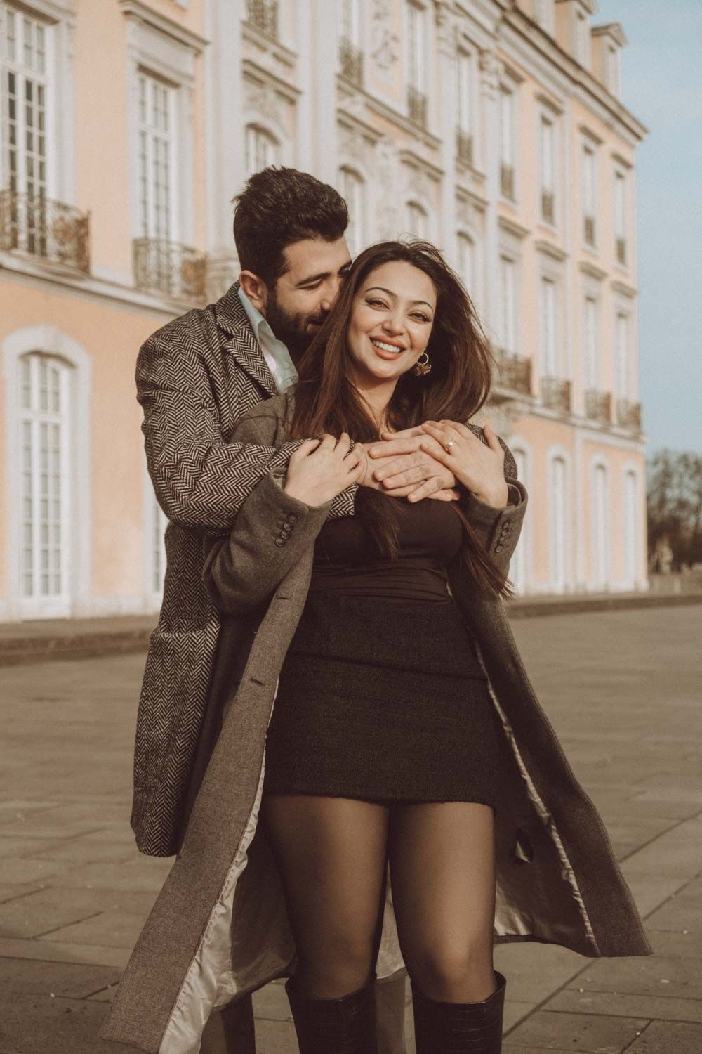 ein Paar mit Blumenstrauß in Hand und lachen zusammen in einer Verlobung Fotoshooting in Brühler Schloss, NRW, Detuschland.