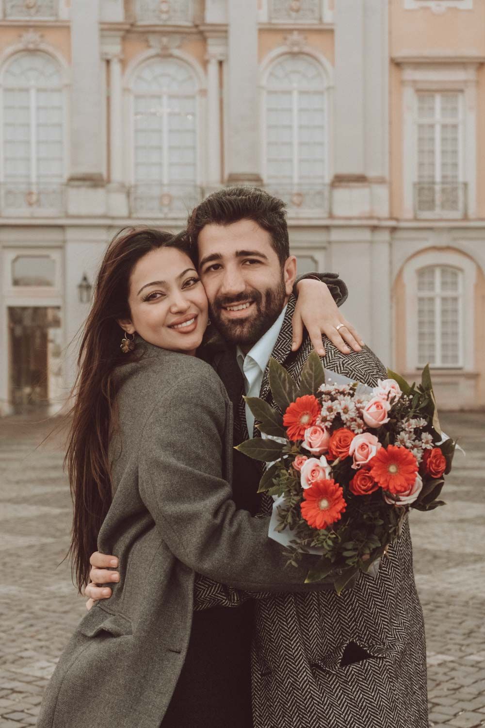 ein Paar mit Blumenstrauß in Hand und lachen zusammen in einer Verlobung Fotoshooting in Brühler Schloss, NRW, Detuschland.