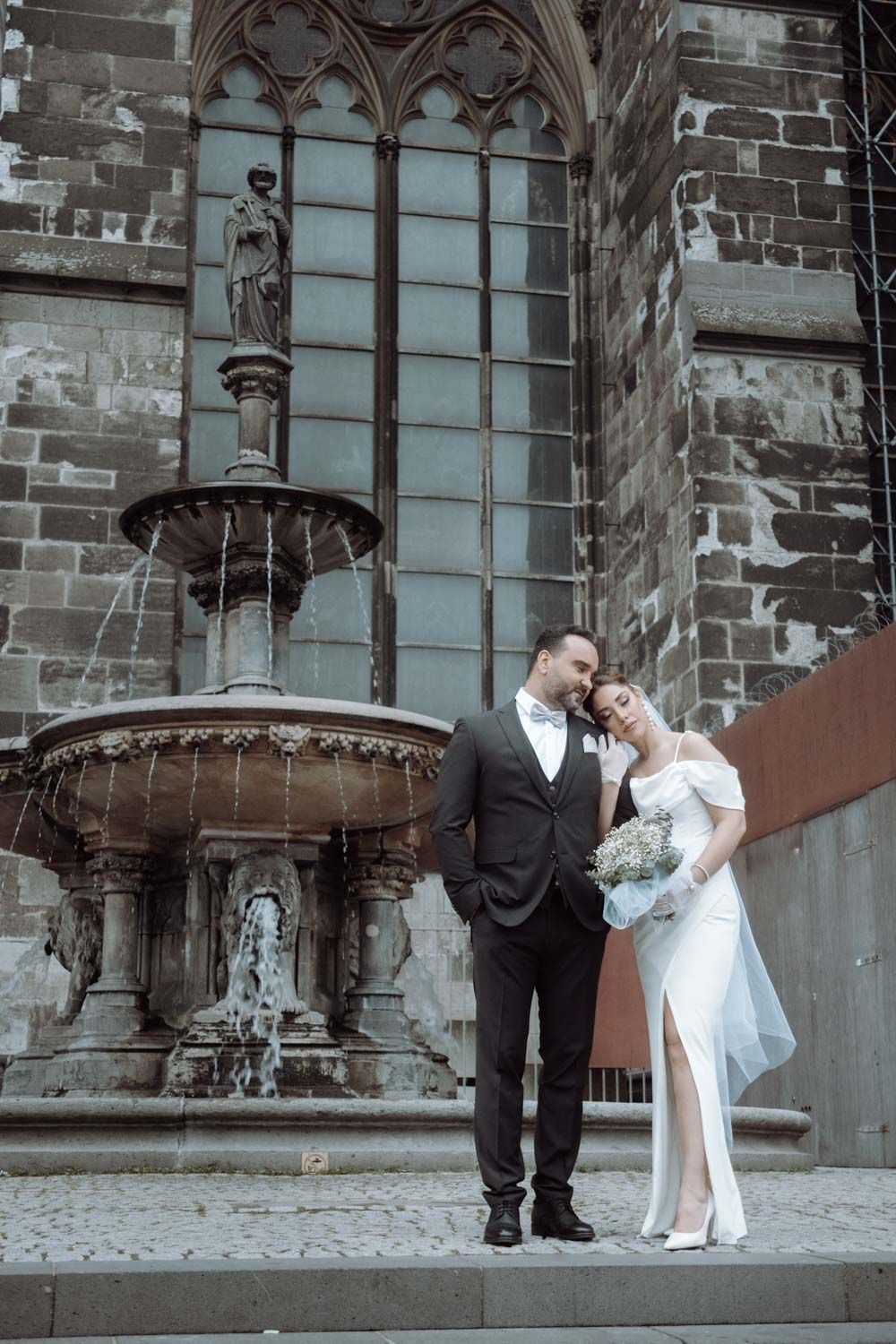 ein Paar mit Posenanleitung in einem Fotoshooting vor der Kirche in einem Trauung Fotoshooting.