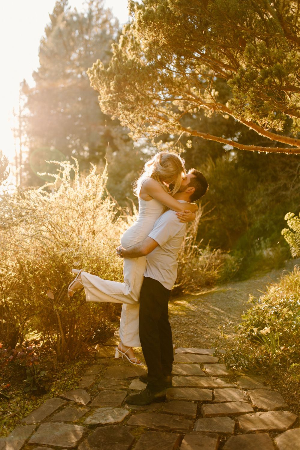 Romantic sunset moment with couple embracing on stone pathway.