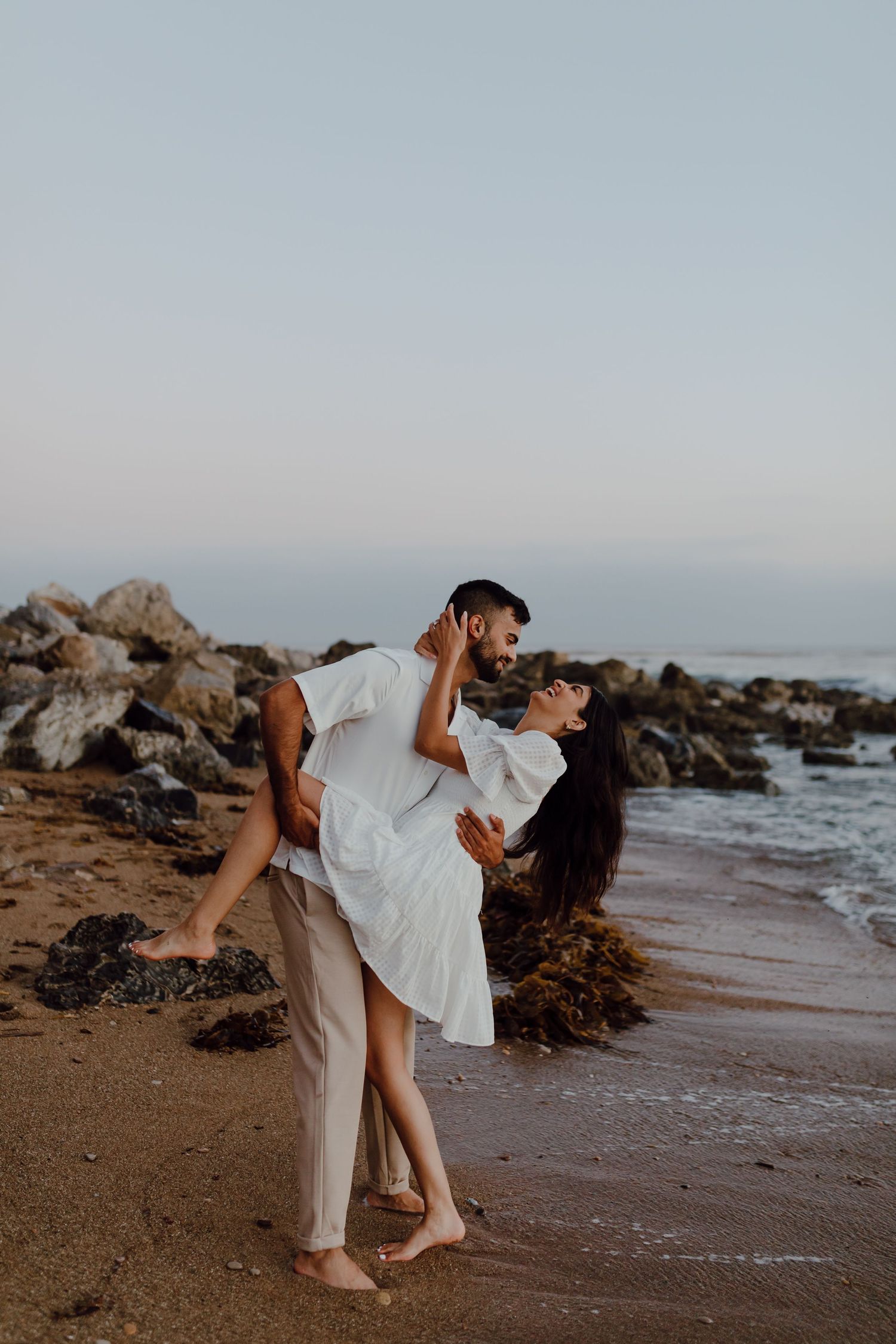 A romantic dance pose on a rocky beach at sunset.