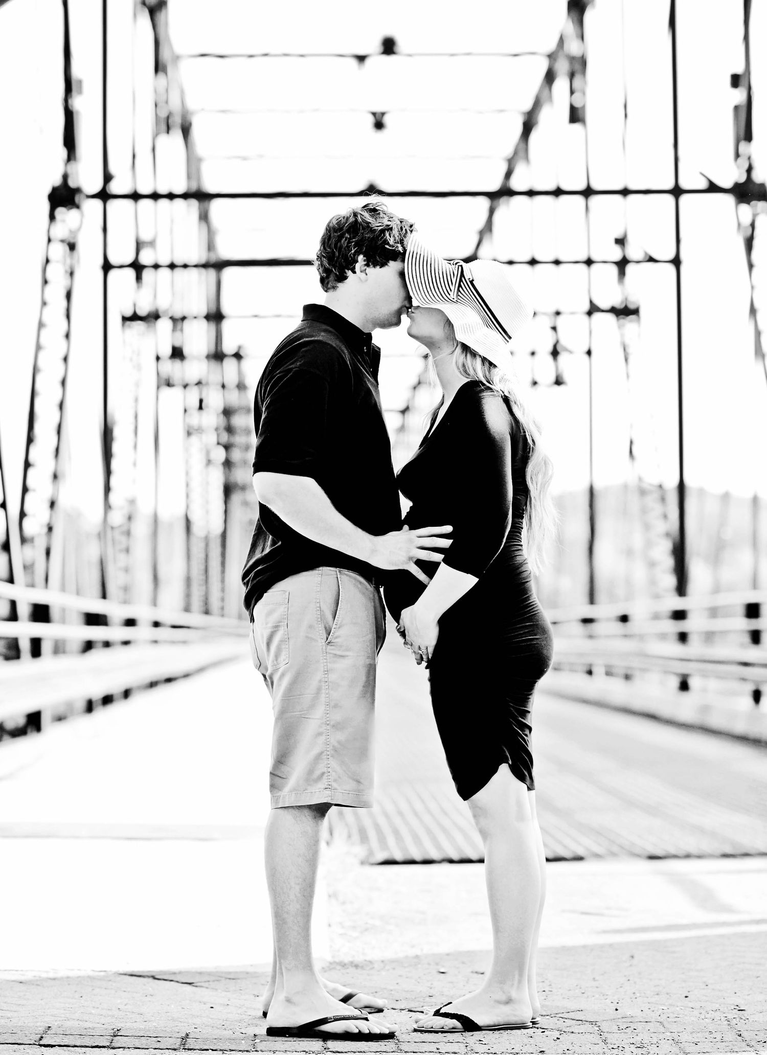 Photograph of a couple, outdoors, in the city embracing on a bridge with hands placed on pregnant belly with newborn arriving soon, York PA