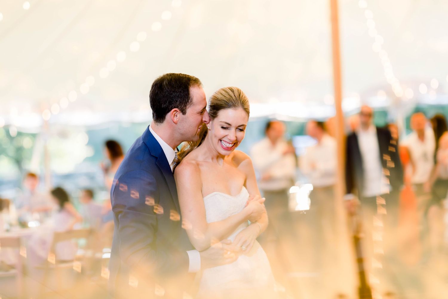 A romantic moment captured under a tent with soft lighting and bokeh effects.