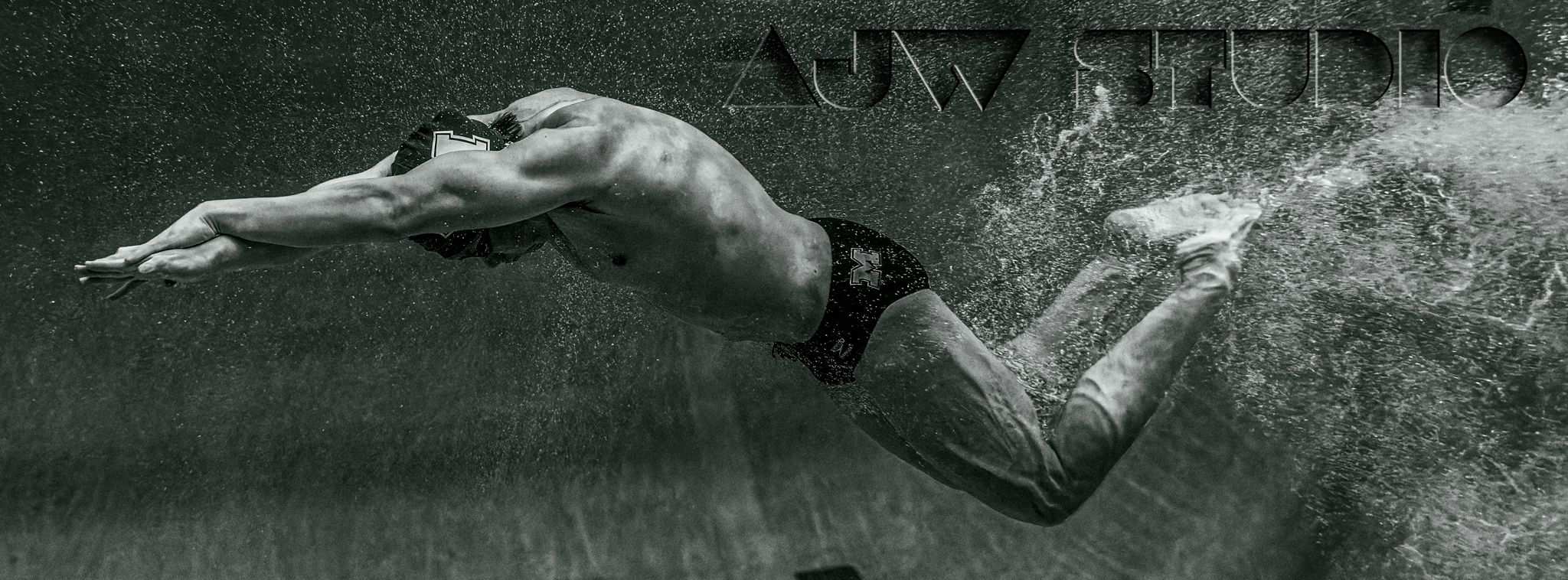 Athletic figure diving into water creating dramatic splash against dark background.