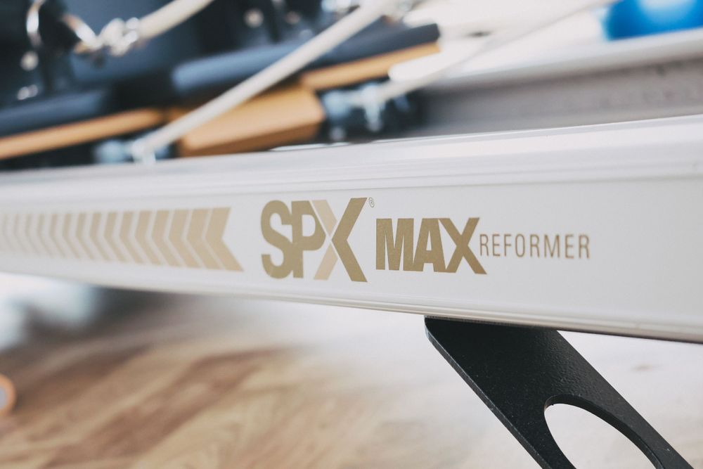 Close-up of SPX Max Reformer Pilates machine branding on white frame.