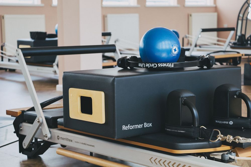 Pilates reformer box with blue exercise ball in a bright fitness studio.
