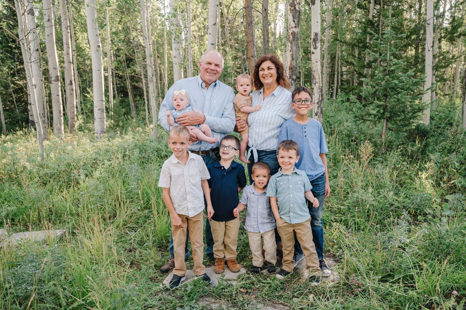 A large family group poses together in an aspen grove during summer.