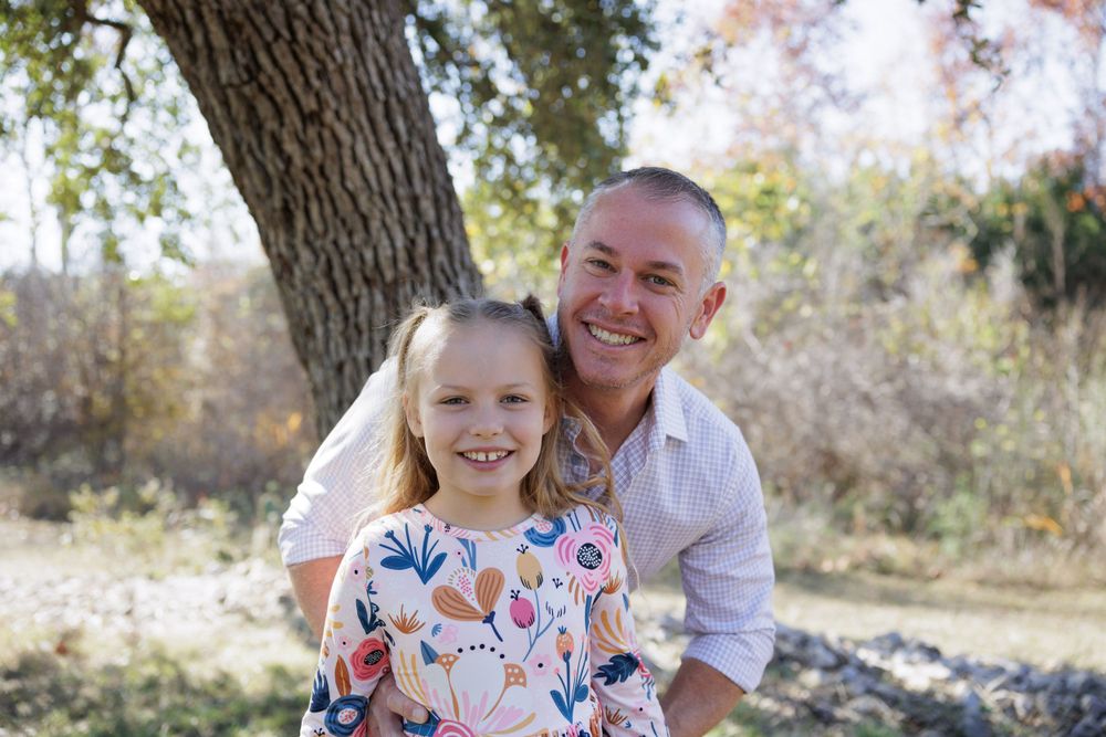 Parent and child in floral dress share happy moment during outdoor family photoshoot.
