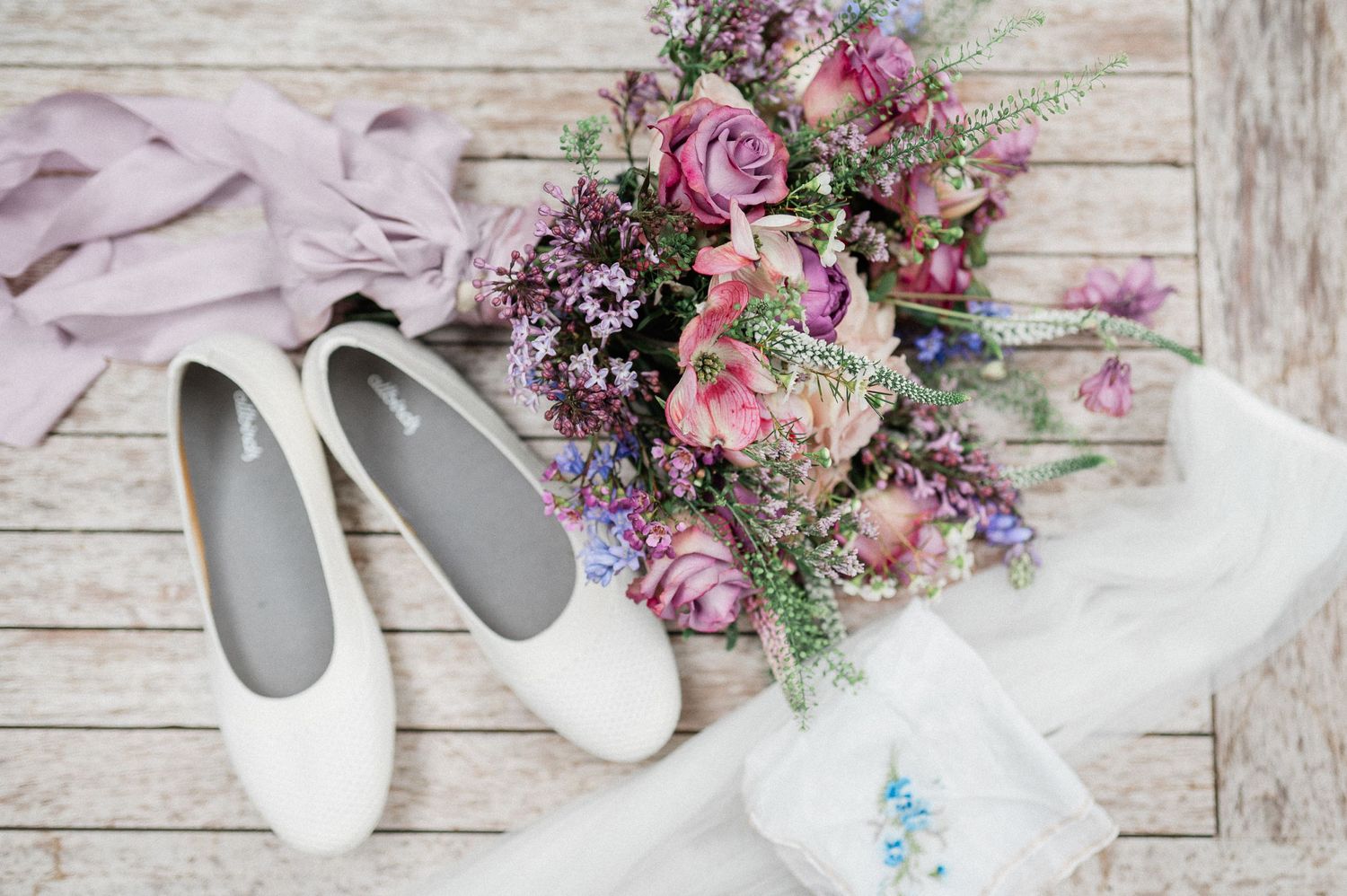 bridal shoes with pink and purple bouquet on wood