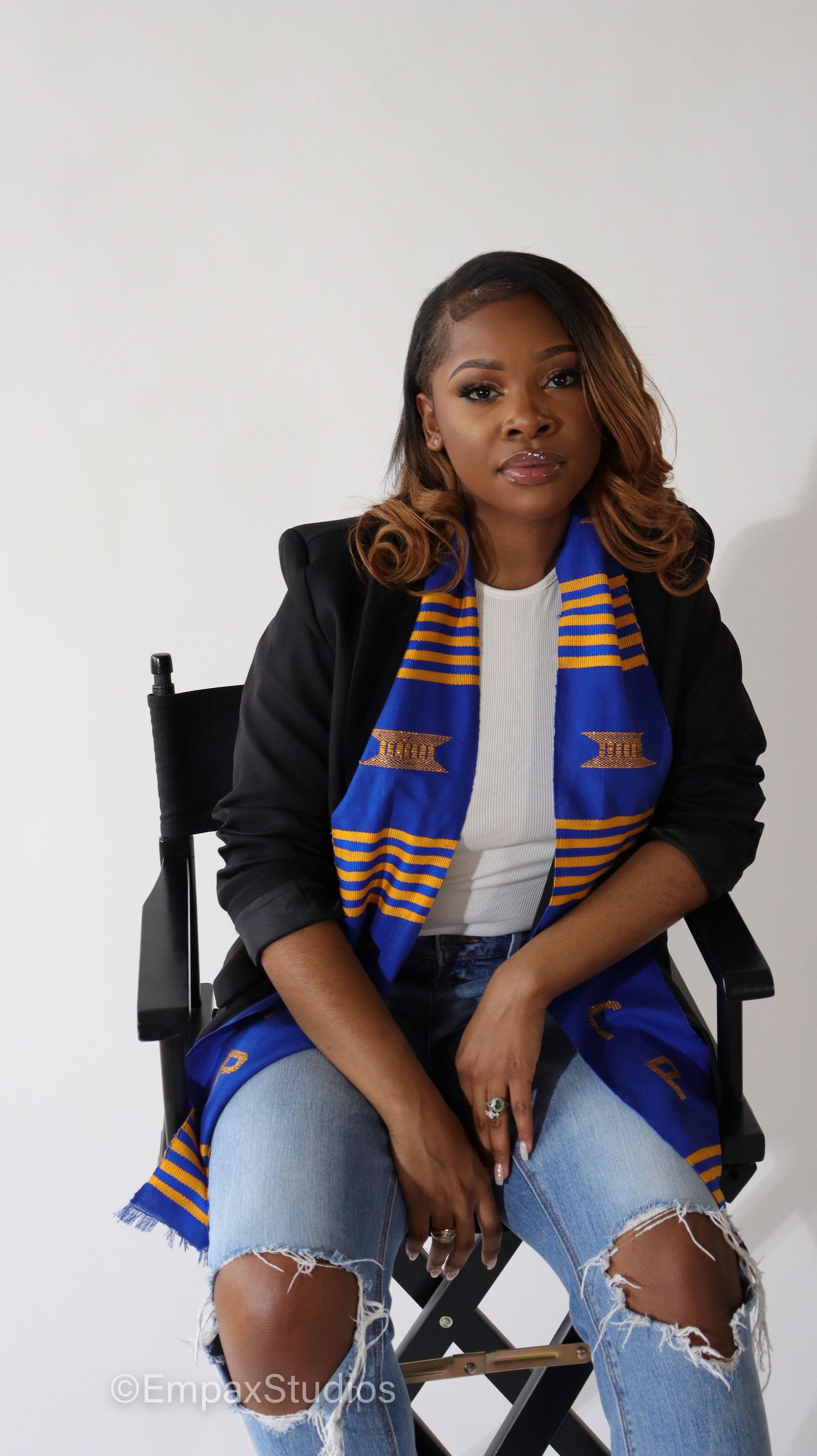 A professional portrait of a graduate wearing a blue and gold sorority stole, showcasing graduation photography by Empax Studios