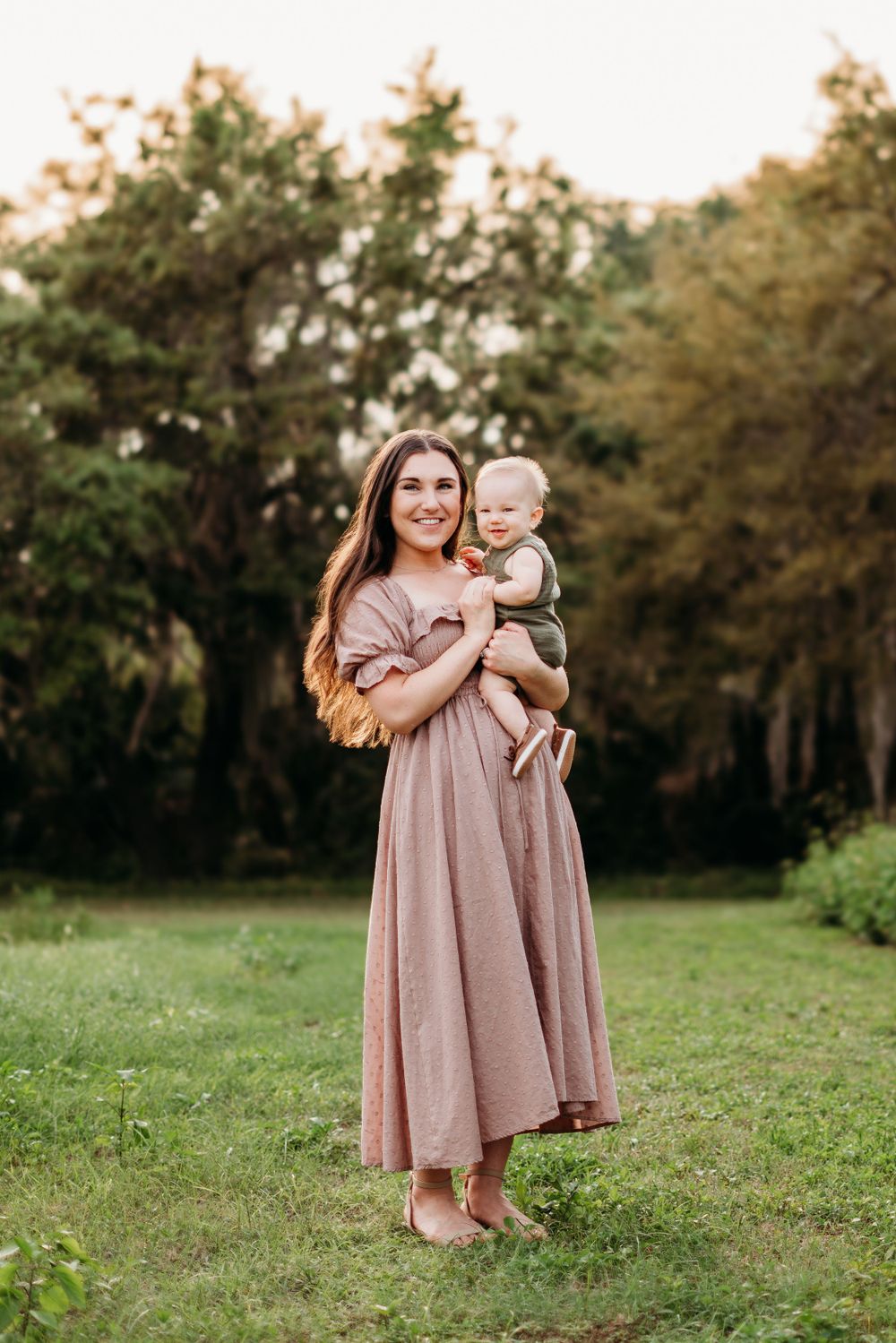 Mother and infant posing in a green field.