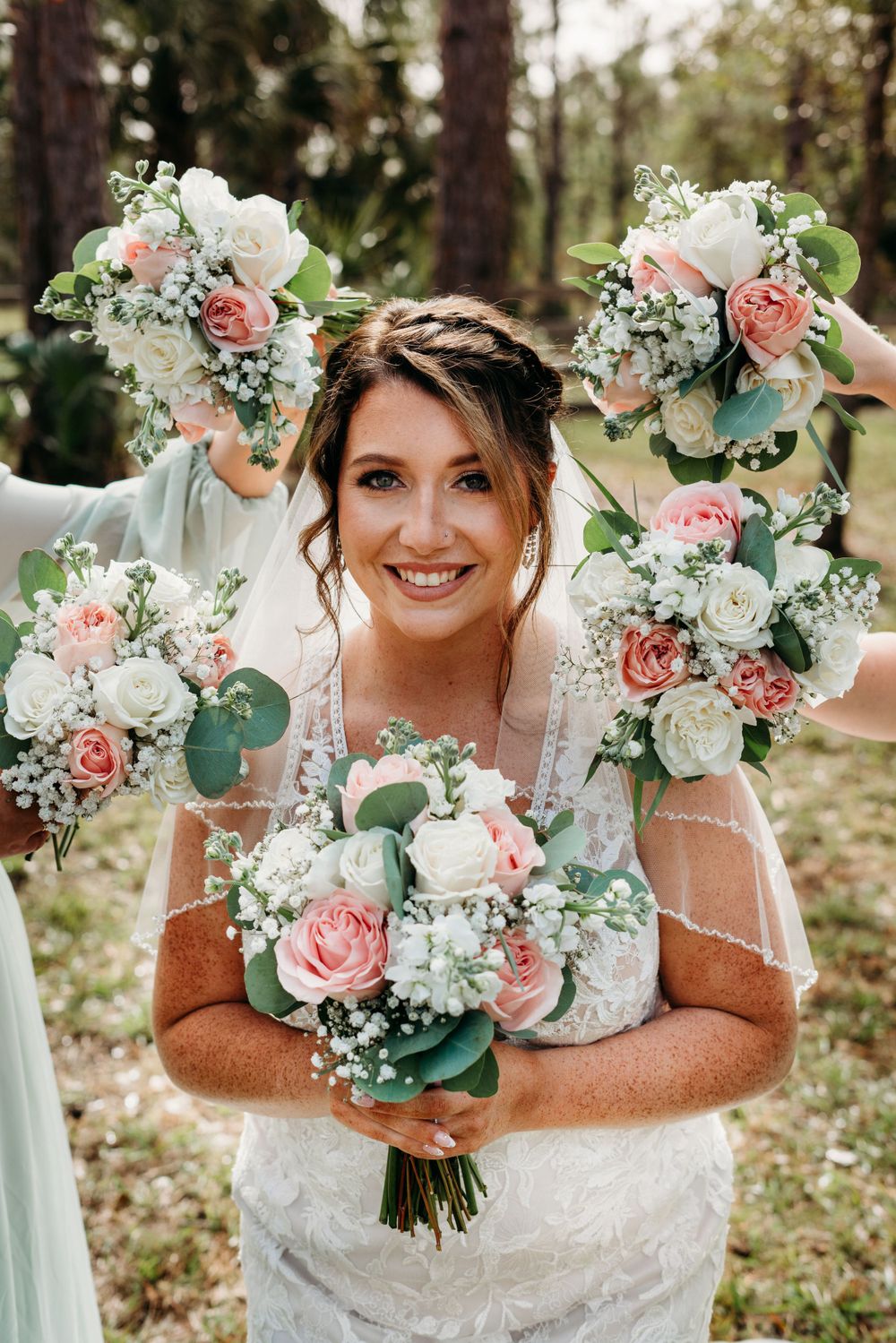 Bride smiling at the camera surrounded by bridesmaids bouquets.