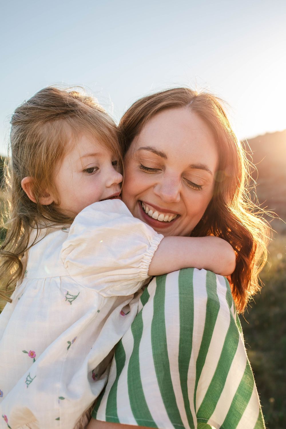 Tender moment between parent and child in warm sunset light.