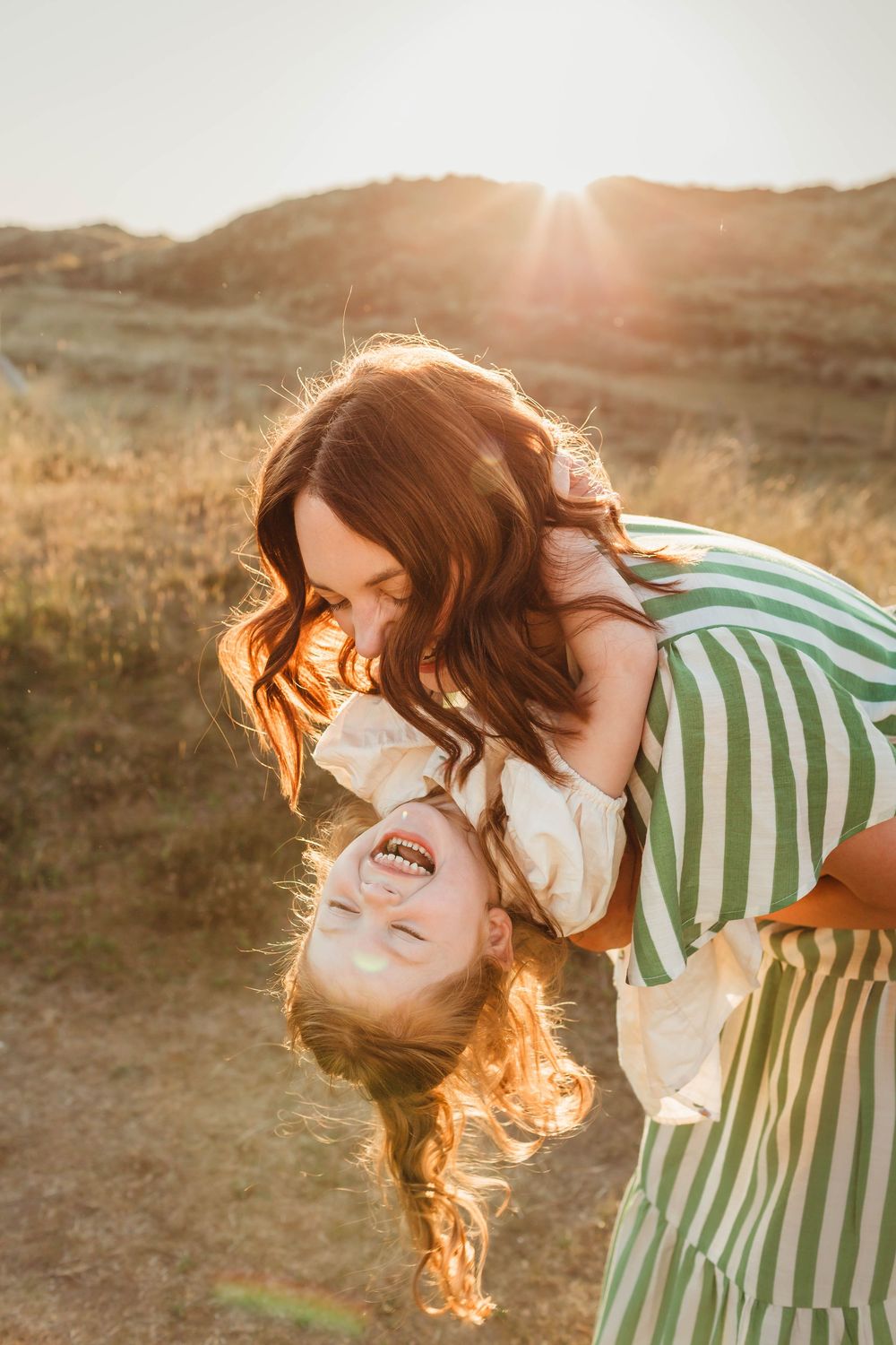 Joyful embrace captured in golden sunset light on hillside.