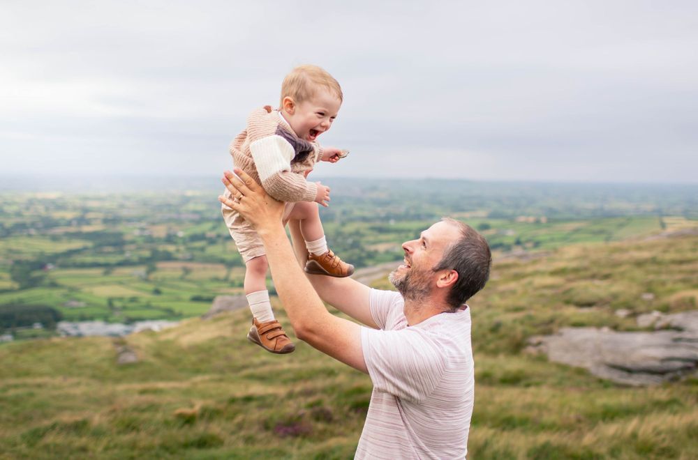 Playful interaction against a backdrop of rolling hills and cloudy skies.