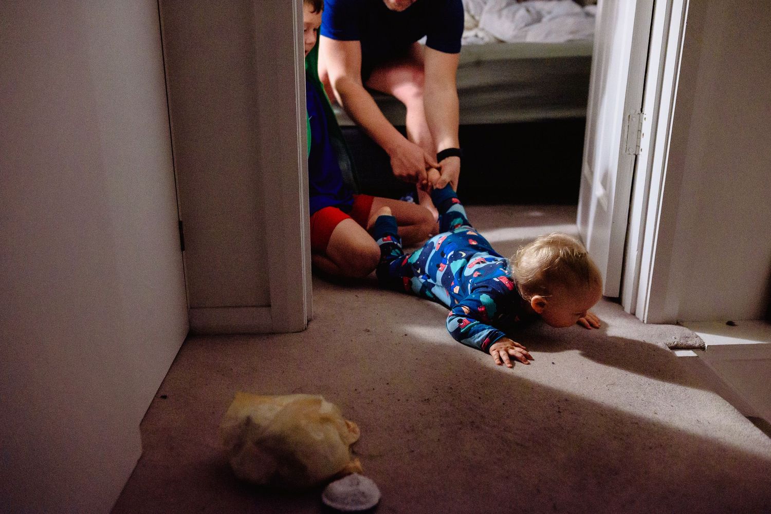 A dimly lit indoor scene with a child crawling near a stuffed toy.