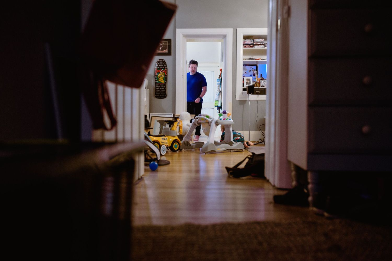 A view through doorways into a sunlit room with toys scattered on the floor.