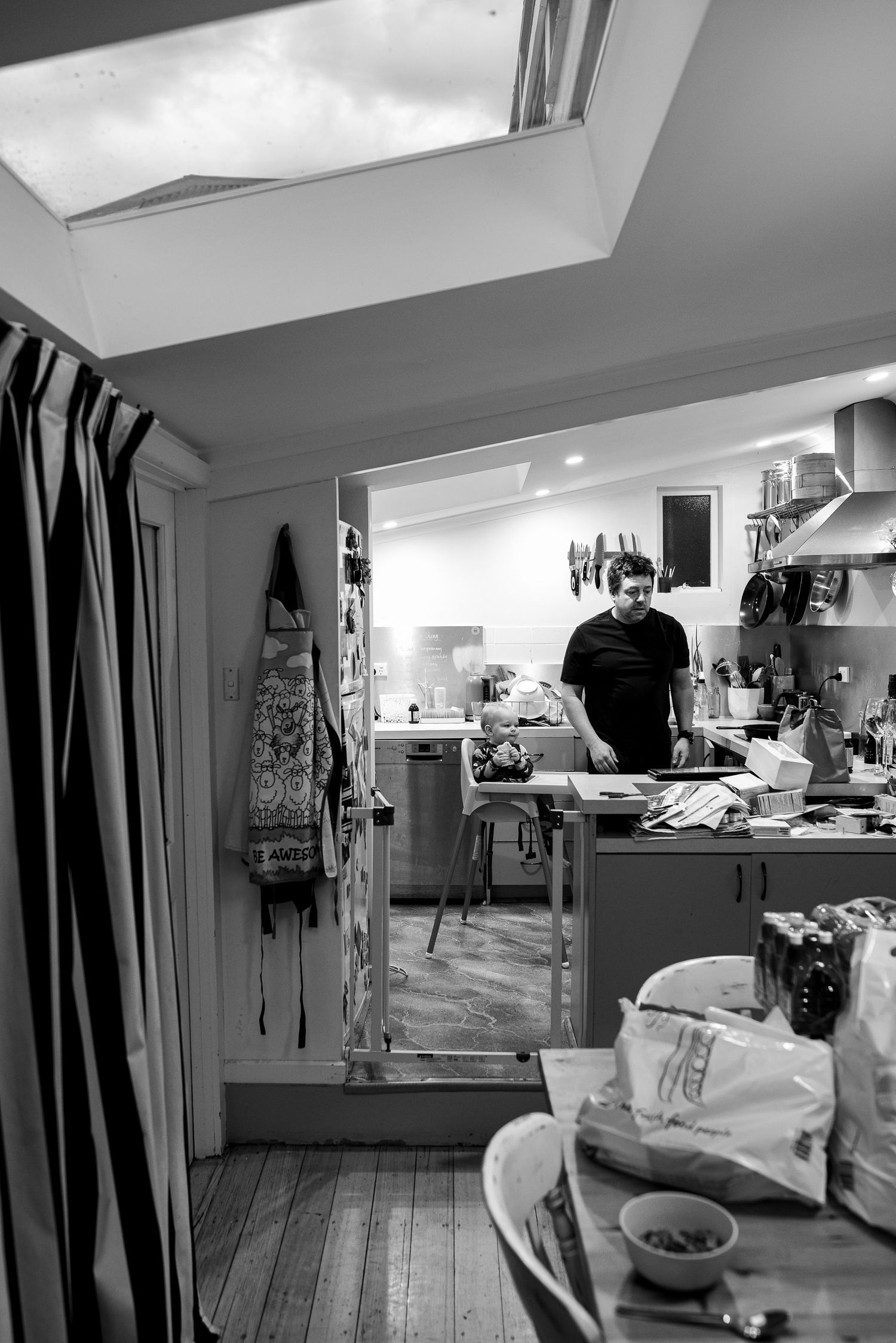 Black and white view of small kitchen with skylight and striped curtains.