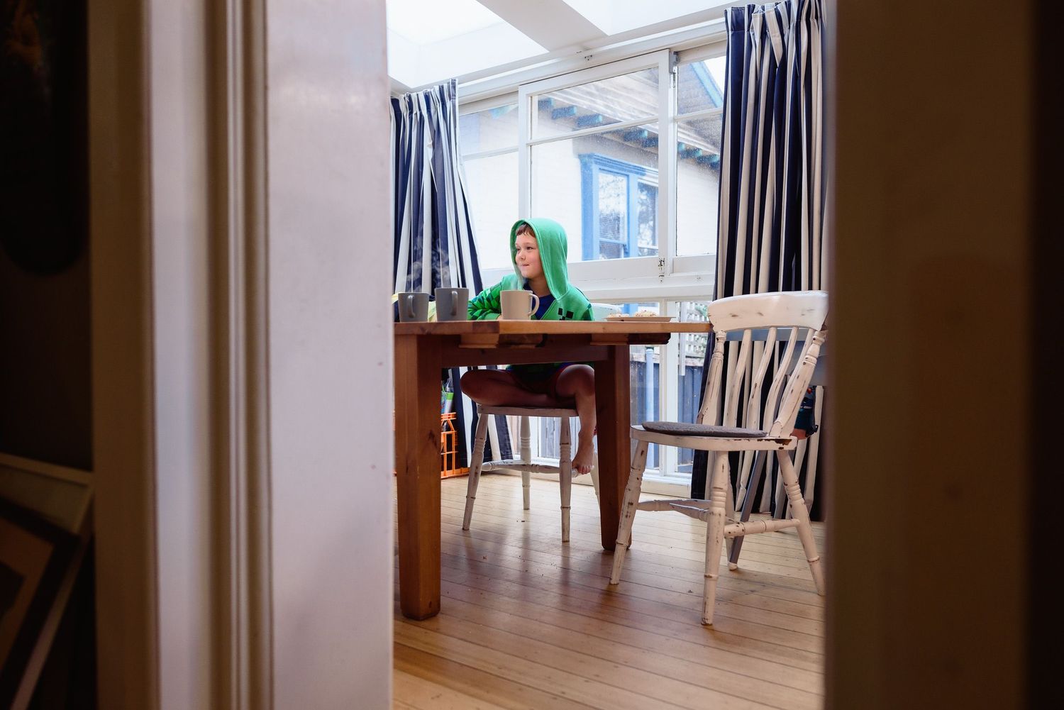 View through doorway of dining area with blue curtains and wooden table.