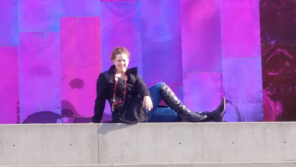 Person sitting on a ledge with vibrant purple lighting effects in the background.