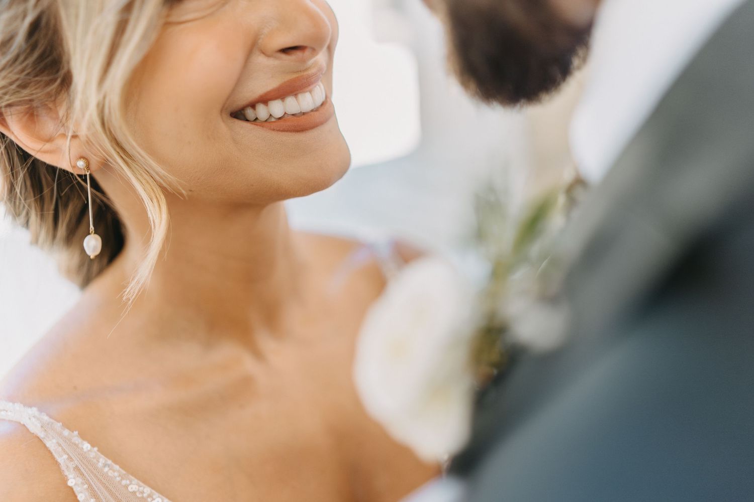 Close-up wedding photo showing joyful smile and white floral boutonniere.