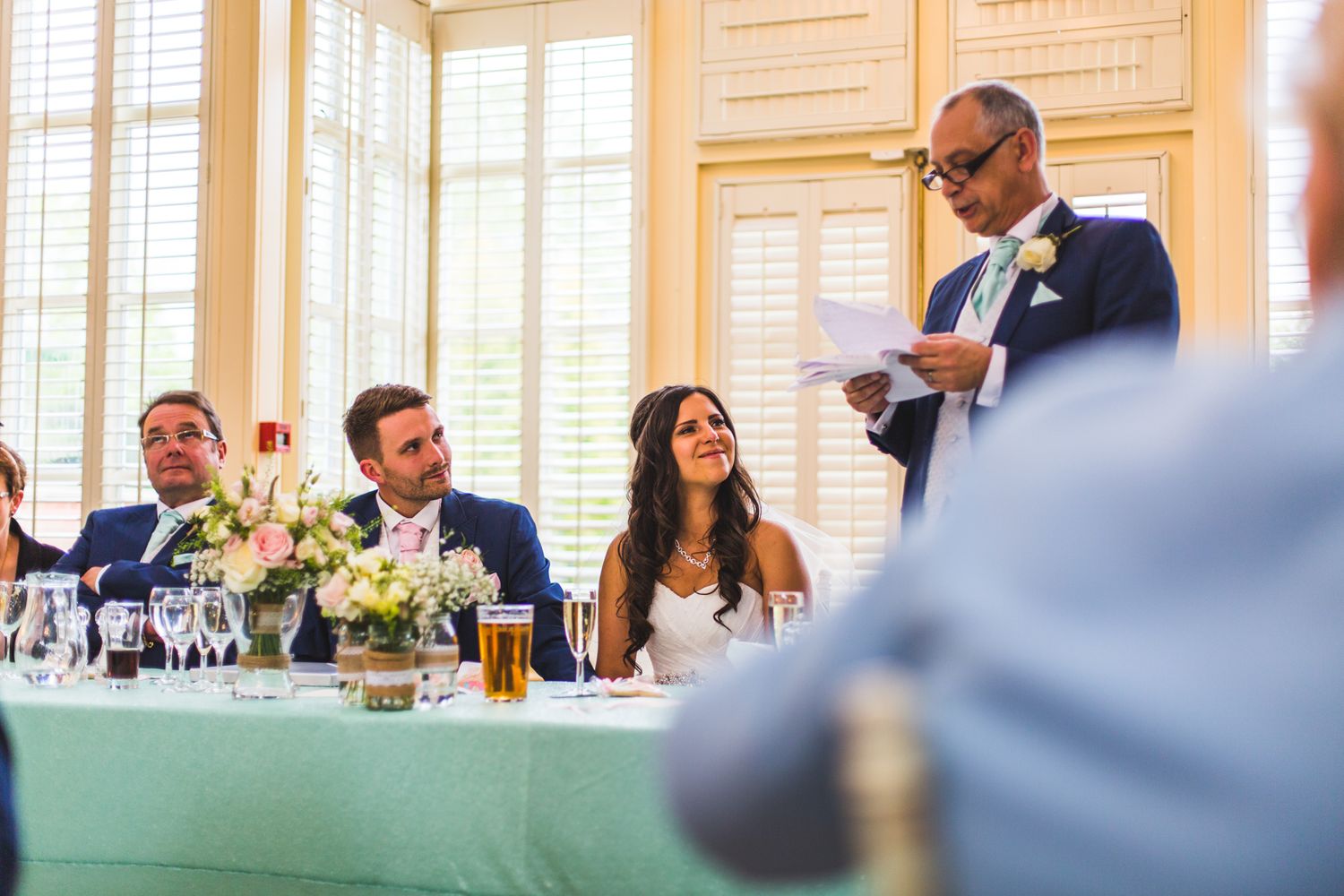 Wedding speech being delivered at an elegant reception with guests seated at decorated tables.
