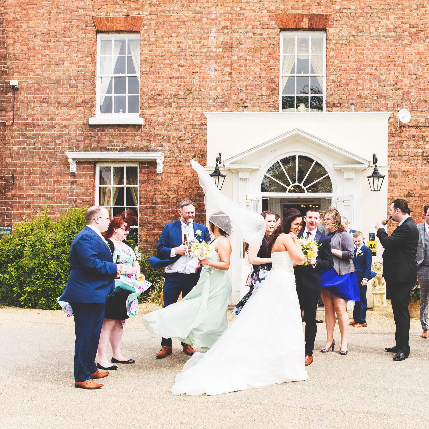 Wedding guests gather outside a historic brick building with Georgian windows and white doorway.