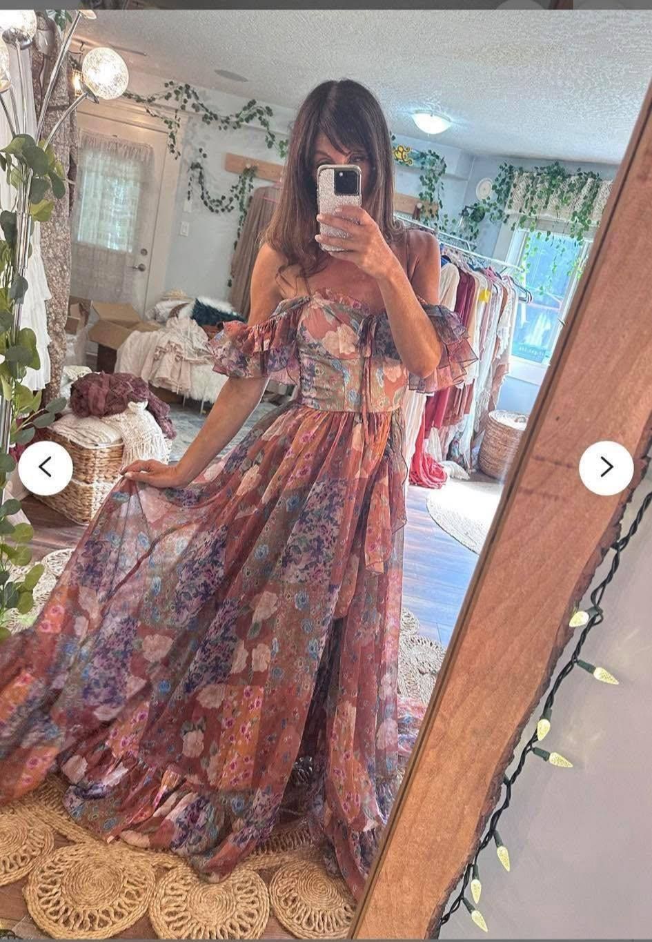 A maxi dress with floral patterns and ruffled details shown in a mirror selfie with bohemian room decor.