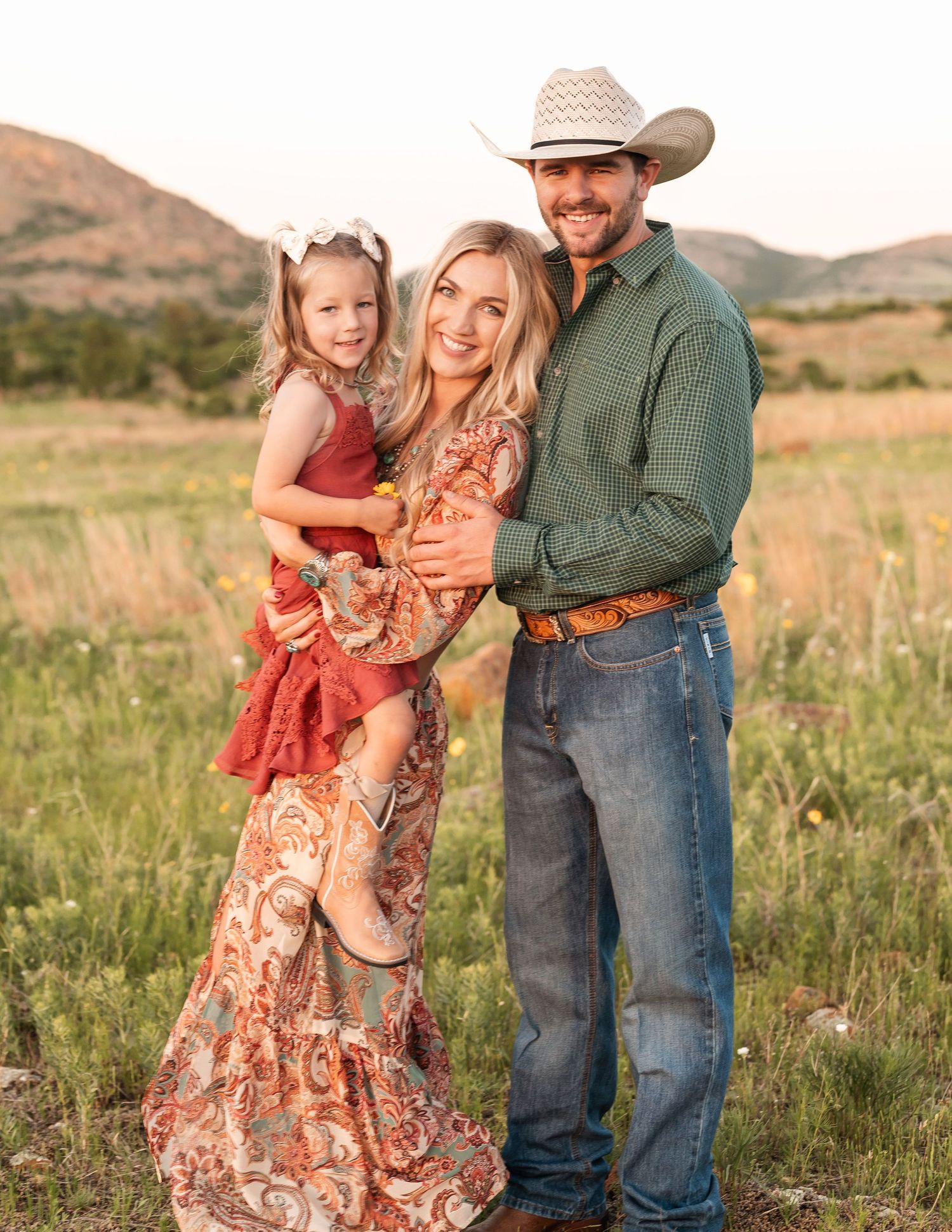 A smiling Jessi, the photographer, and her family standing in a sunlit meadow.