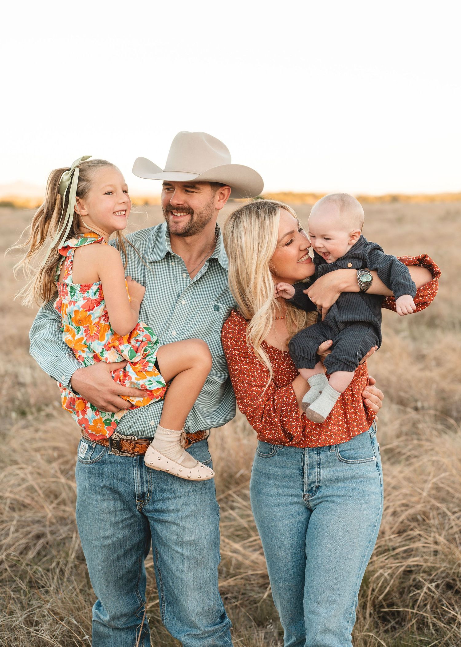 A smiling Jessi, the photographer, and her family standing in a sunlit meadow.