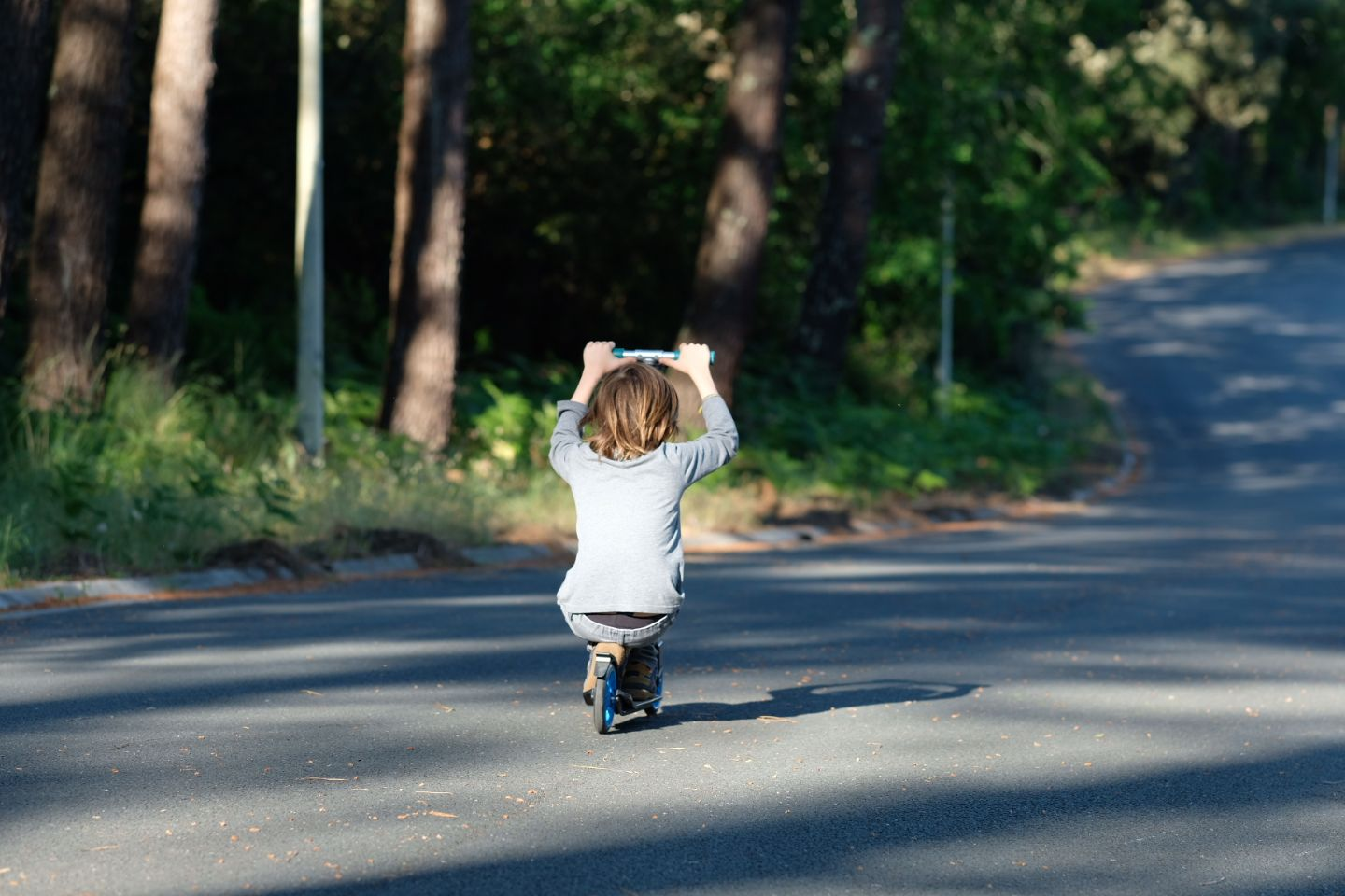 Small figure runs down empty street surrounded by trees.
