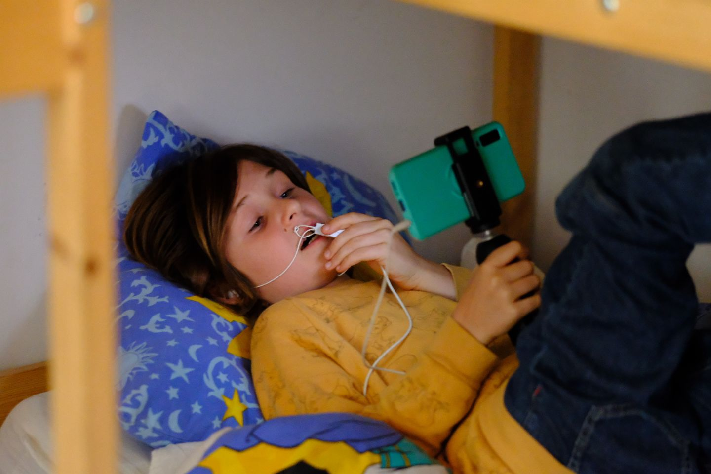 Person in yellow sweater lying down while using mobile device.