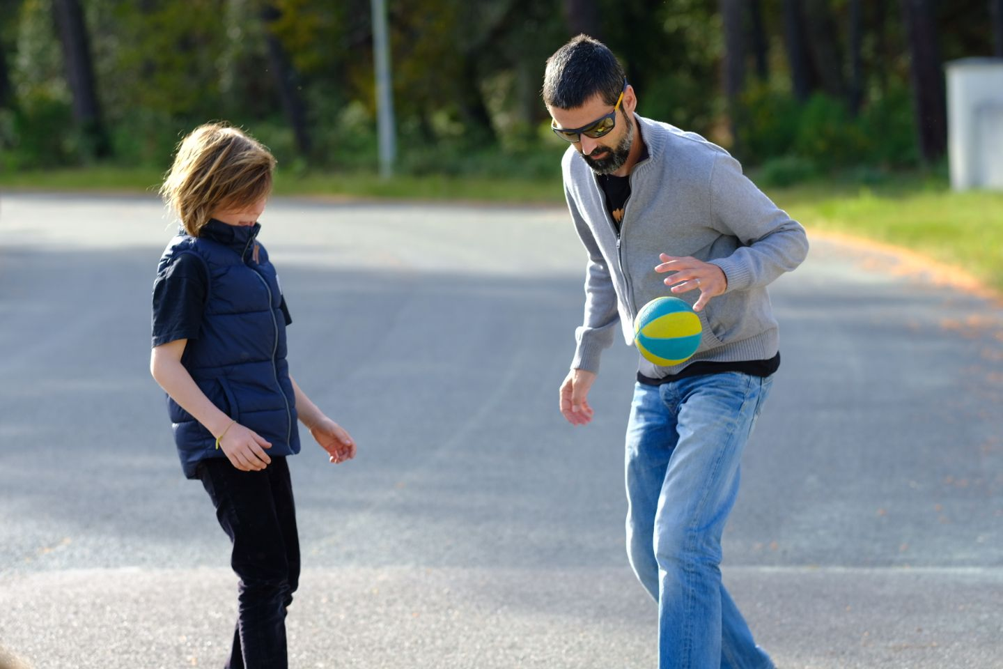 Two people play with a ball on an empty suburban street.