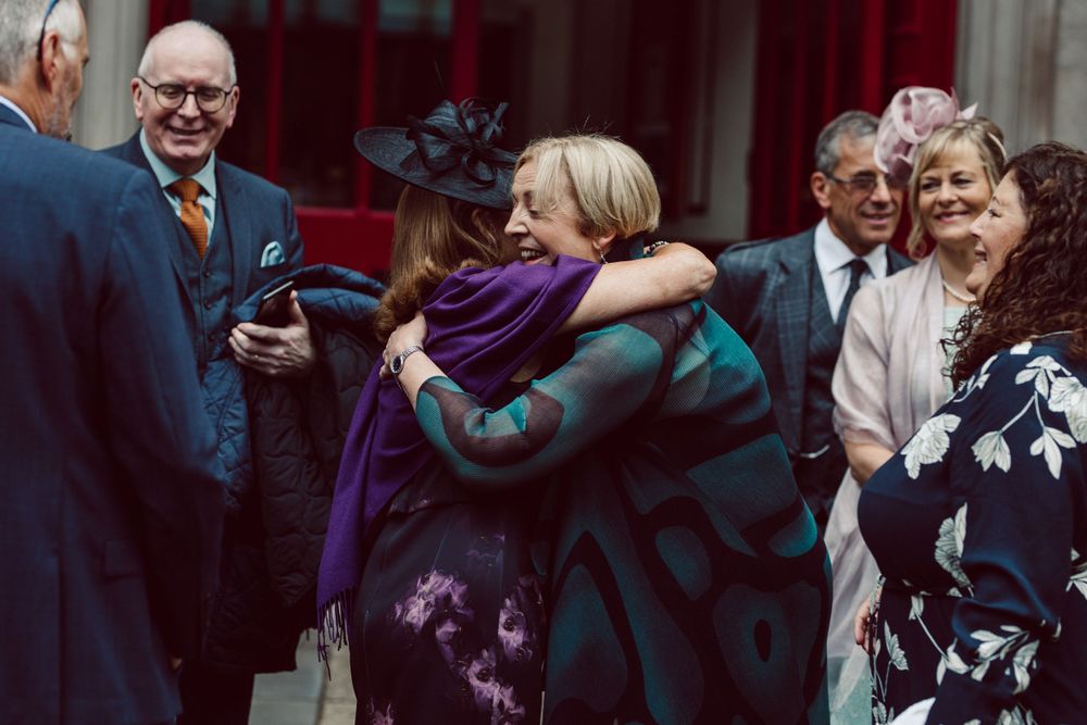 Wedding guests share warm embraces and congratulations outside the venue.