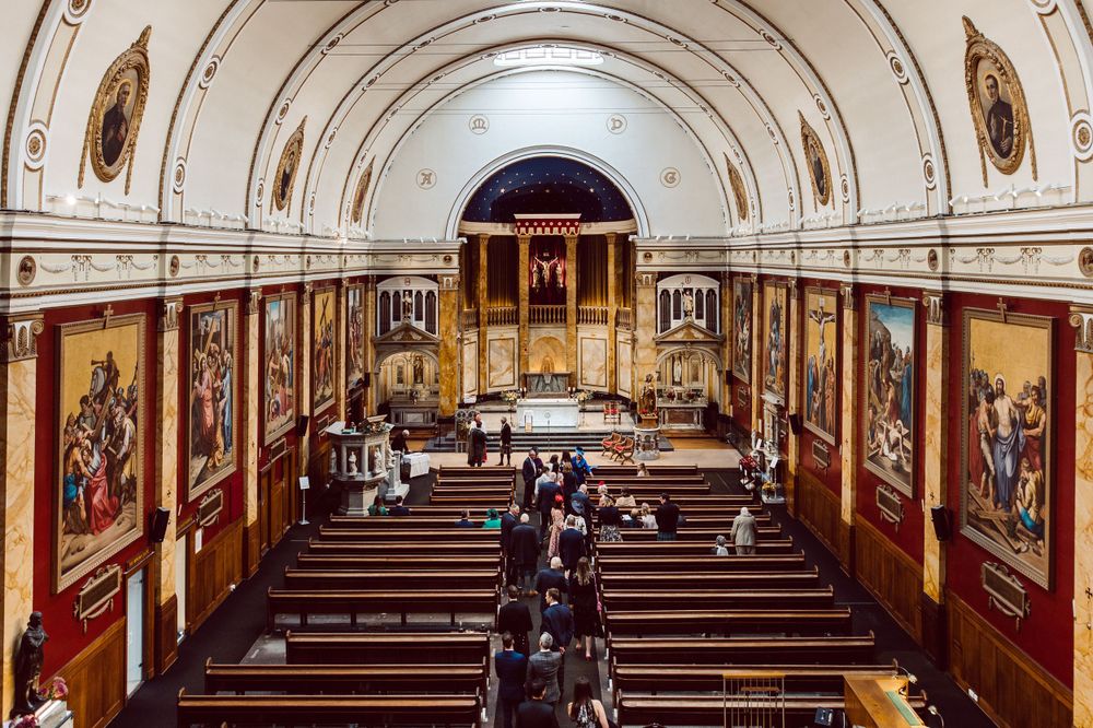 Interior of grand church with vaulted ceiling and wooden pews in traditional architecture.