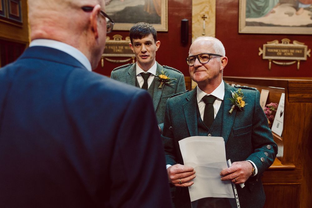 Men in formal attire share documents in an ornate church interior.