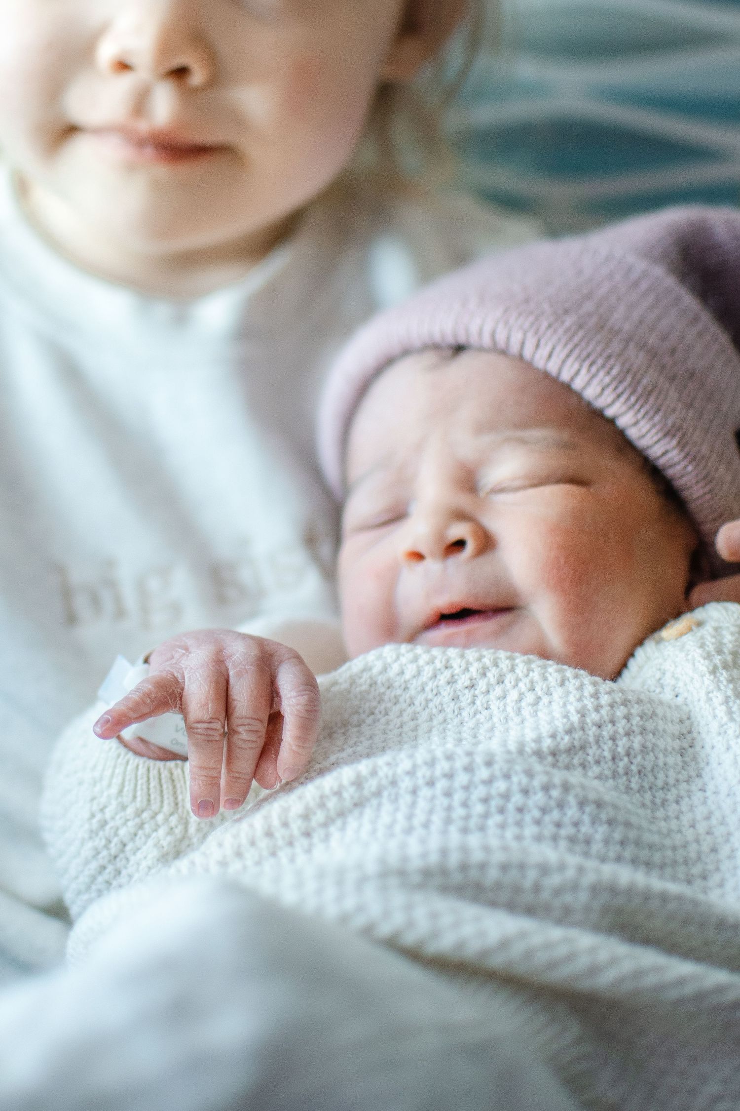 Close up of sleeping newborn in pink knit hat and white blanket.