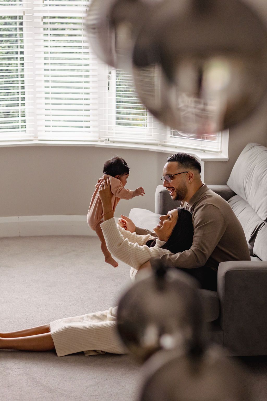 A couple cradles their newborn in their living room during a documentary-style new family photoshoot at home