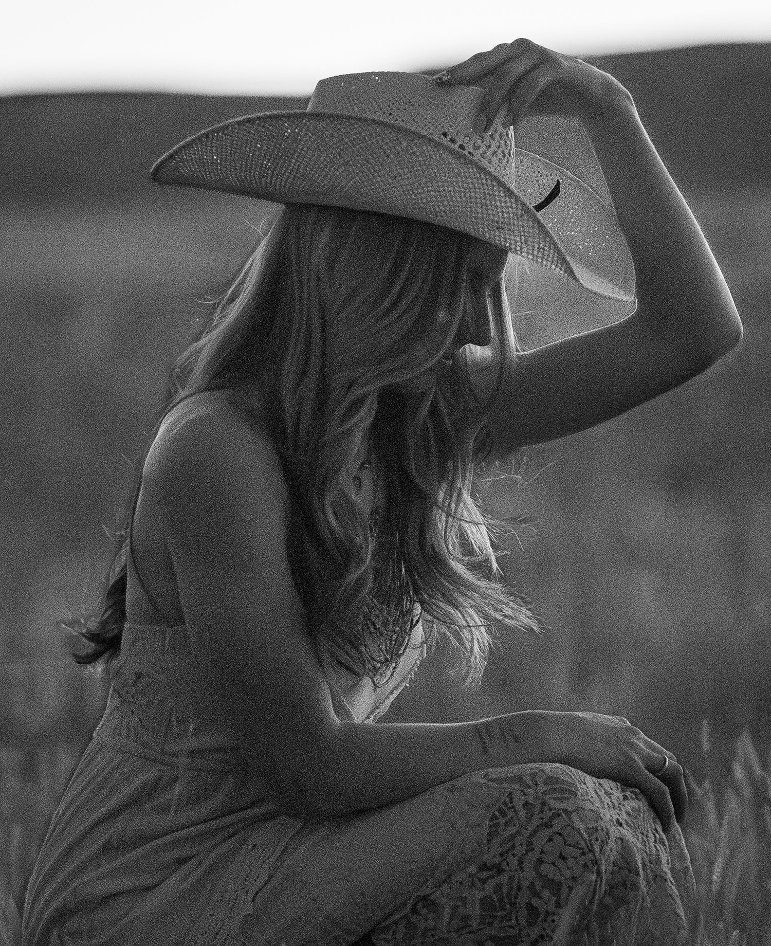 Silhouette of a woman in a cowboy hat against a dreamy black and white background.