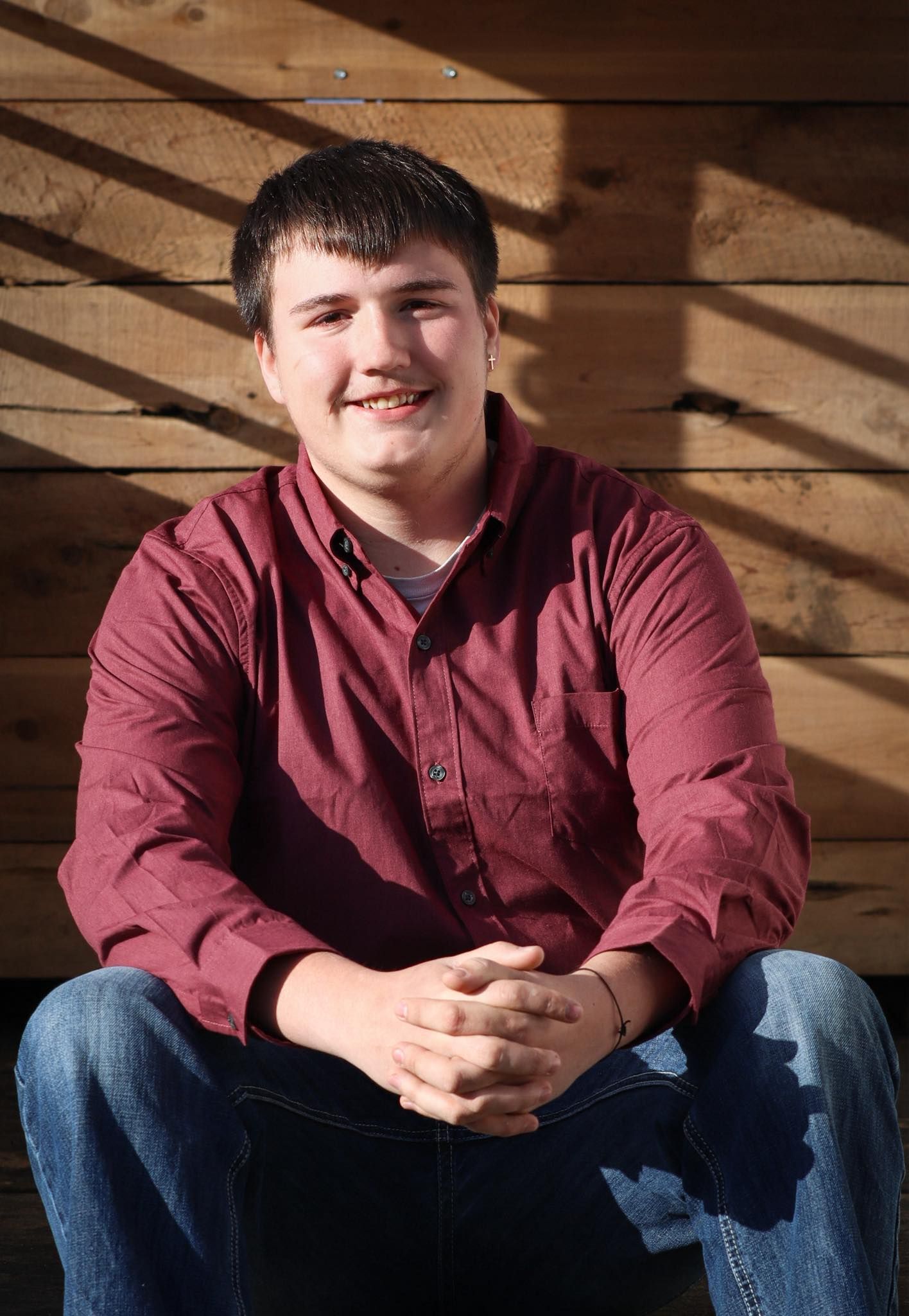 Portrait against wooden wall backdrop with dramatic shadows and lighting.