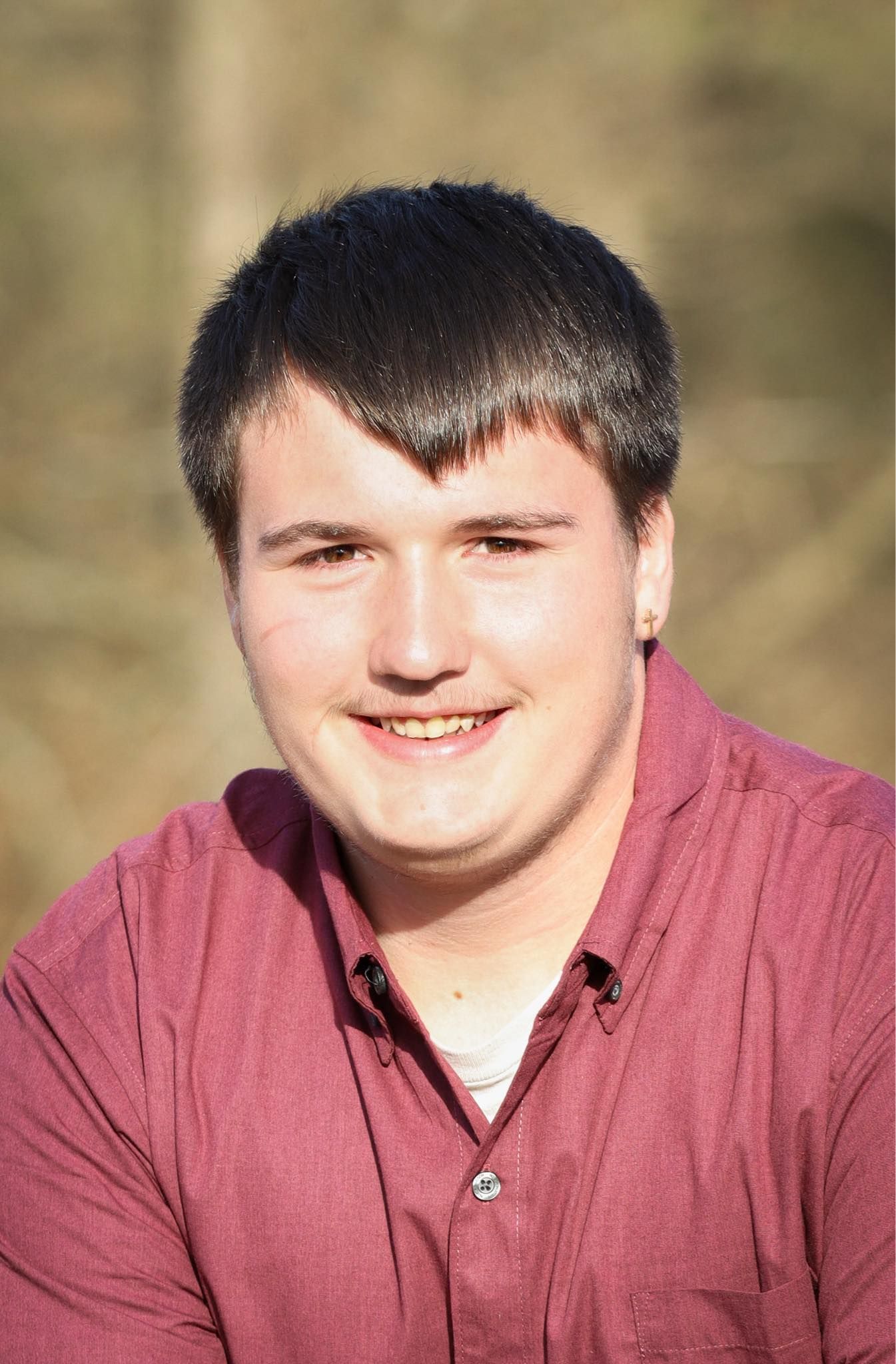 Close-up outdoor portrait of someone wearing a burgundy collared shirt.