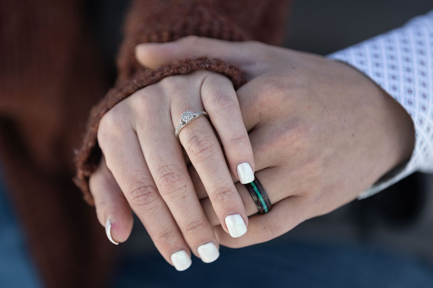 Close-up photo of hands with white nail polish and an engagement ring with diamond solitaire.