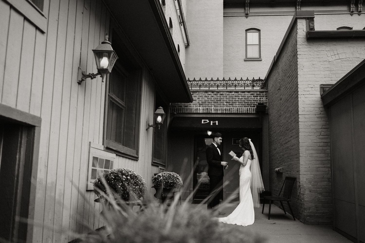 Modern wedding couple poses against industrial backdrop in formal attire.