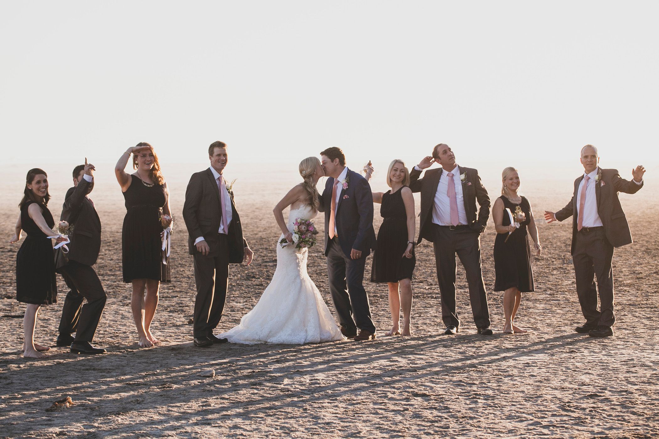 Mike & Stephanie doing a fun pose with their bridal party on Kommetjie beach, Cape Town, S.A. on their wedding day