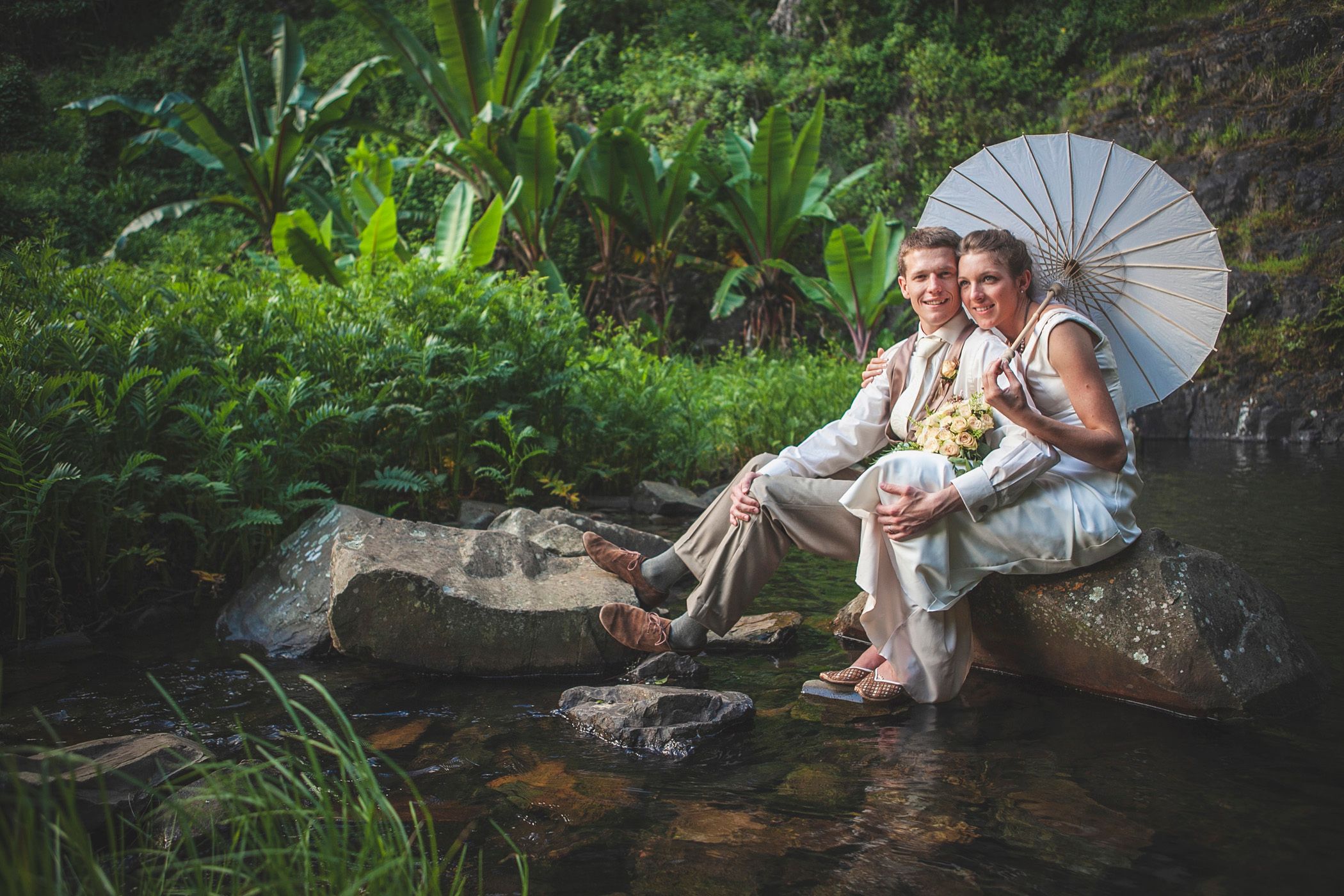 Beautiful bride Meg, with husband Tom, holding a Japanese umbrella under the Bridal Veil Falls in Chimanimani, Zimbabwe