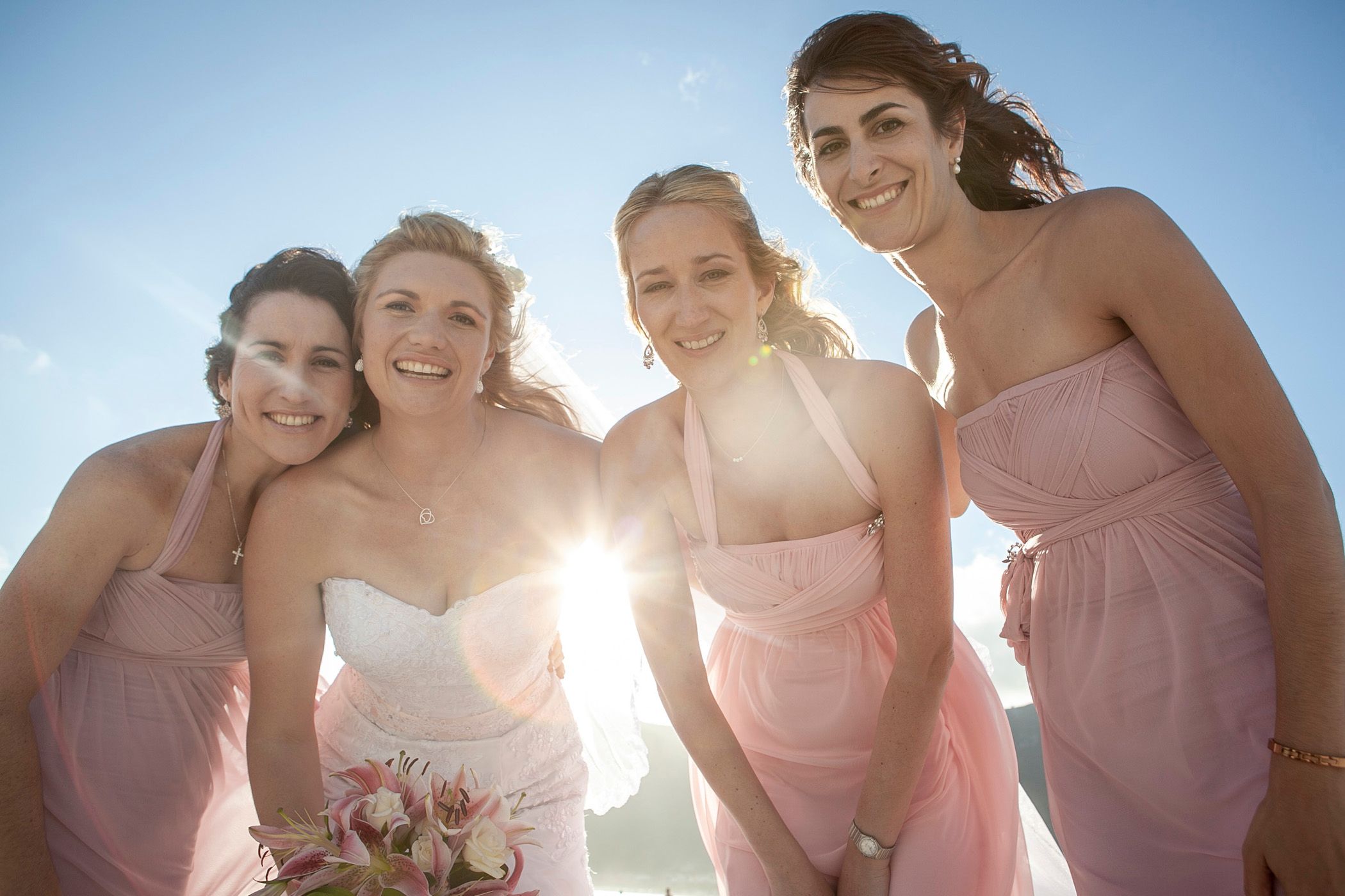 Maryanne and her bridesmaids posing for a photo (with flare!) on Hout Bay beach on her wedding day at Monchique.