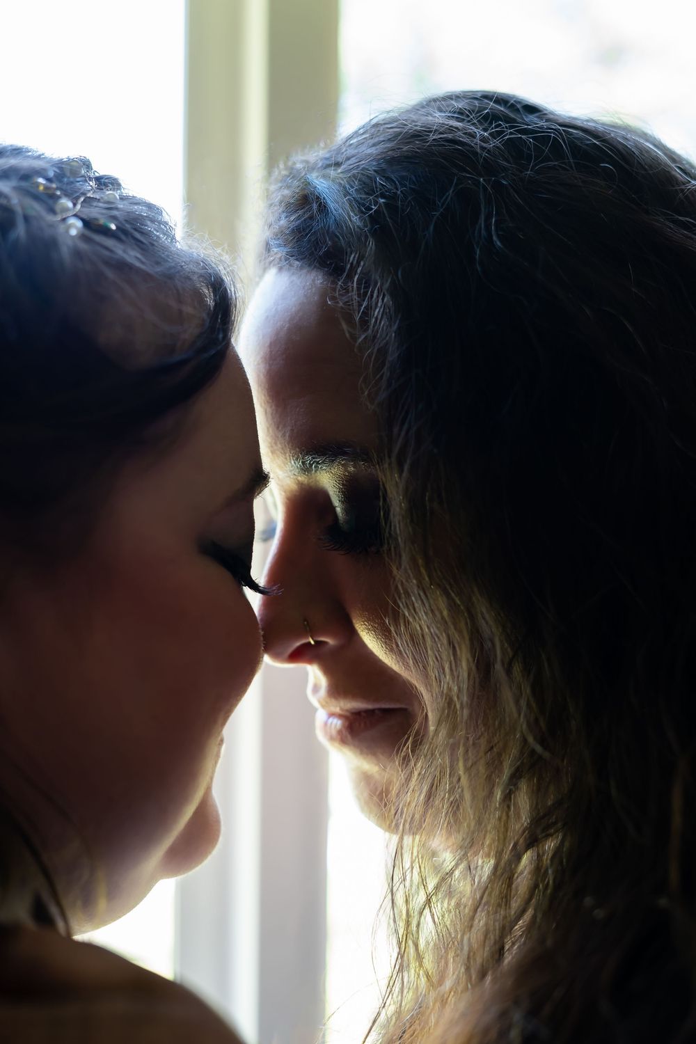 Two silhouettes in profile against window light appear to share a tender moment in a series of intimate photos. LGBTQ couple. West Virginia
